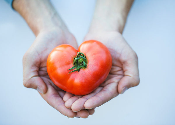 Hands holding a heart-shaped tomato